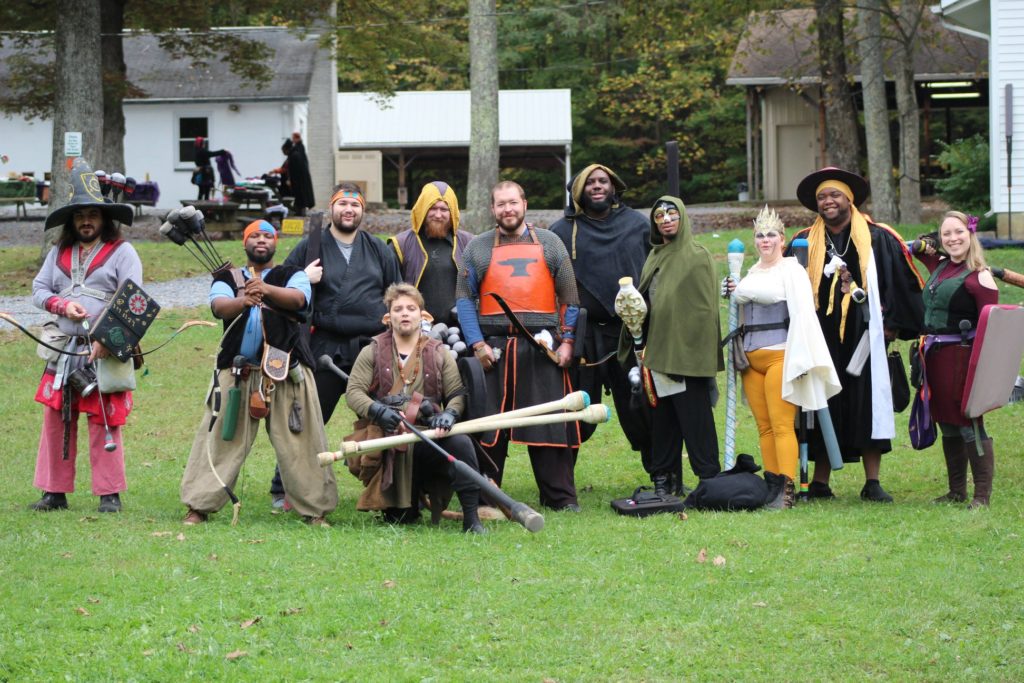 A group of people stand smiling on green grass.